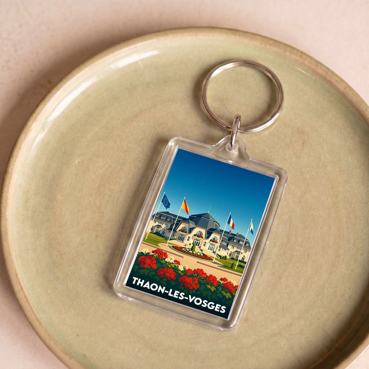 Porte-clés souvenir de la ville de Thaon-les-Vosges avec une illustration stylisée.