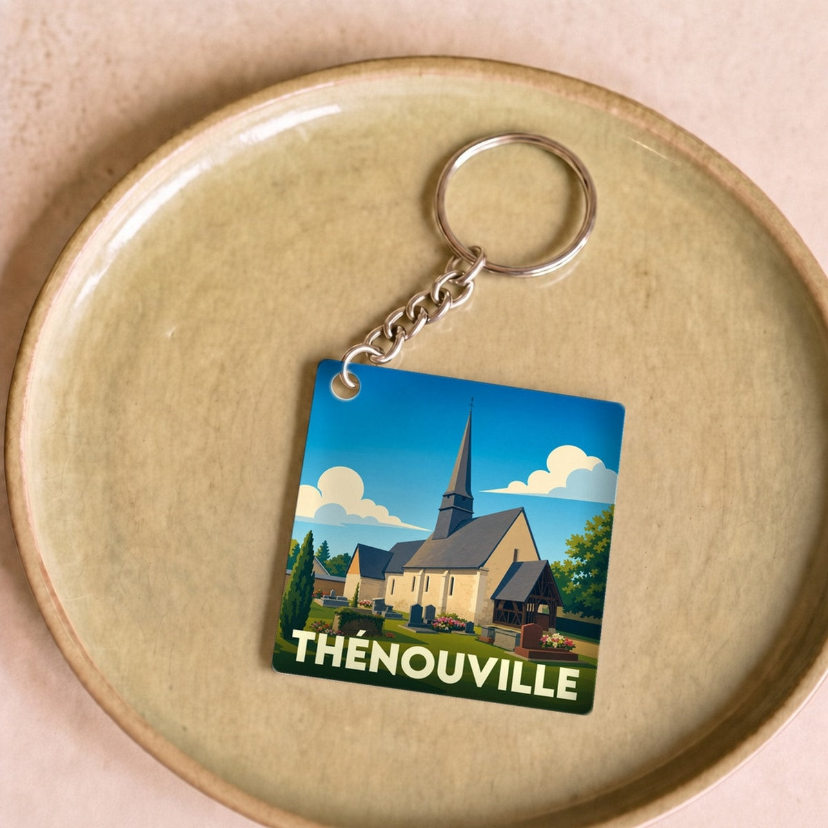 Porte-clés souvenir de la ville de Thénouville avec une illustration stylisée de son église.