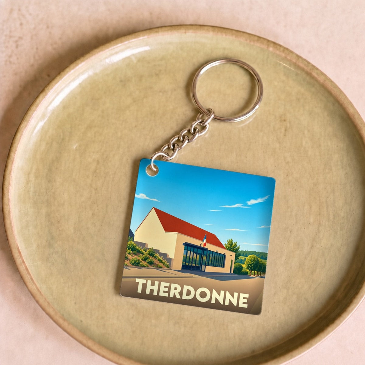Porte-clés souvenir de la ville de Therdonne avec une illustration stylisée.