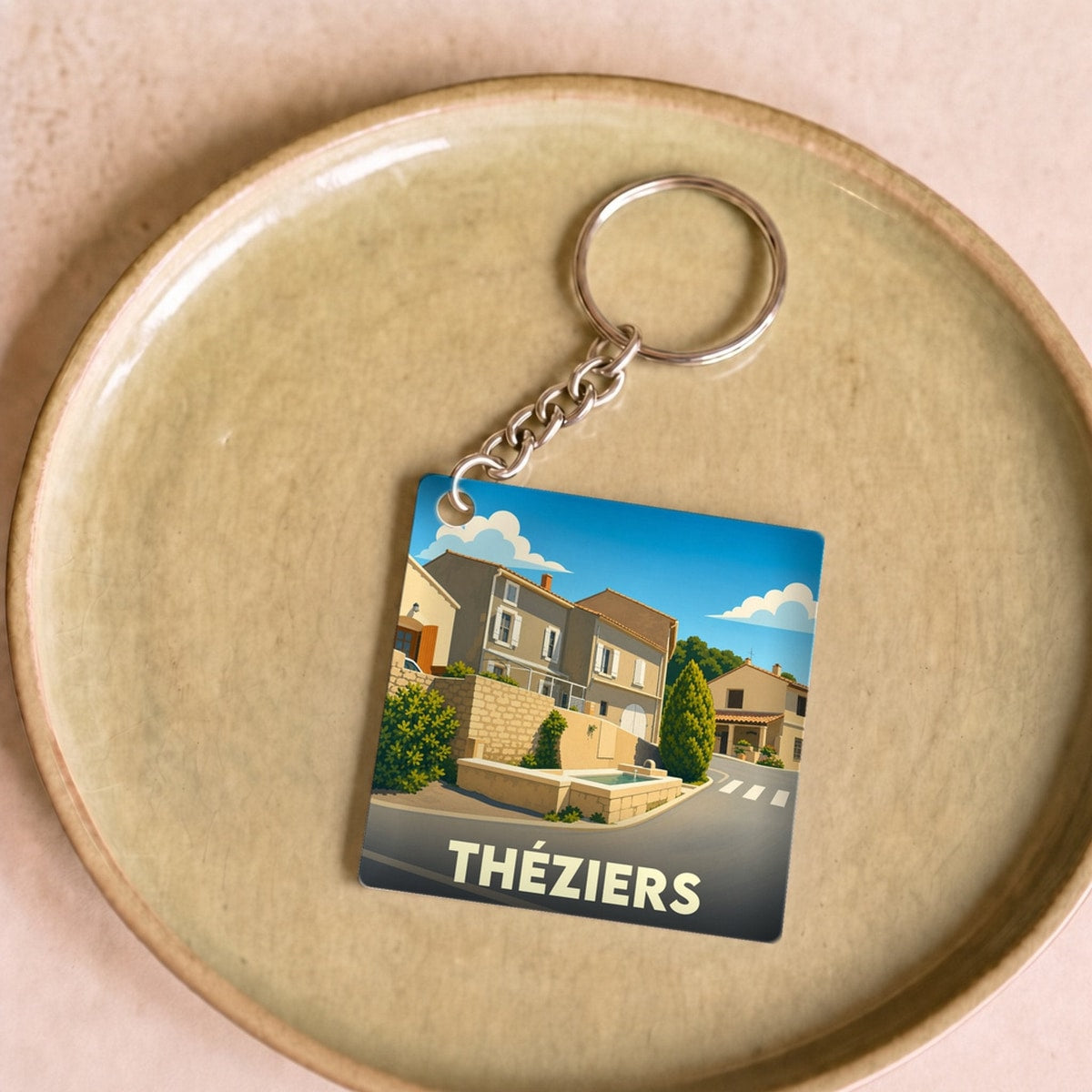 Porte-clés souvenir de la ville de Théziers avec une illustration stylisée.
