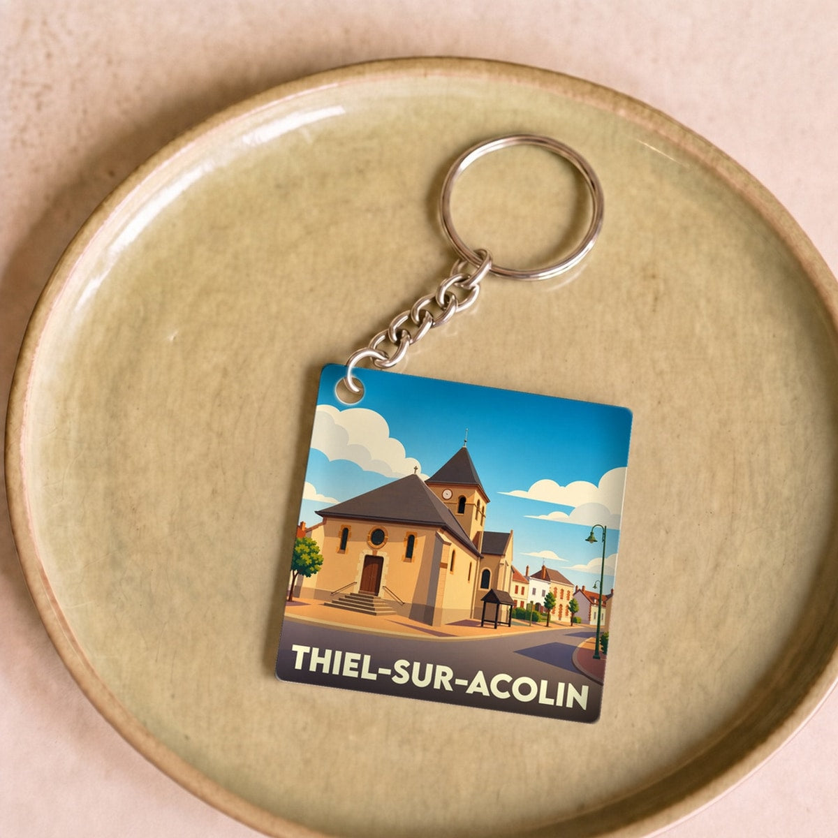 Porte-clés souvenir de la ville de Thiel-sur-Acolin avec une illustration stylisée de son église.