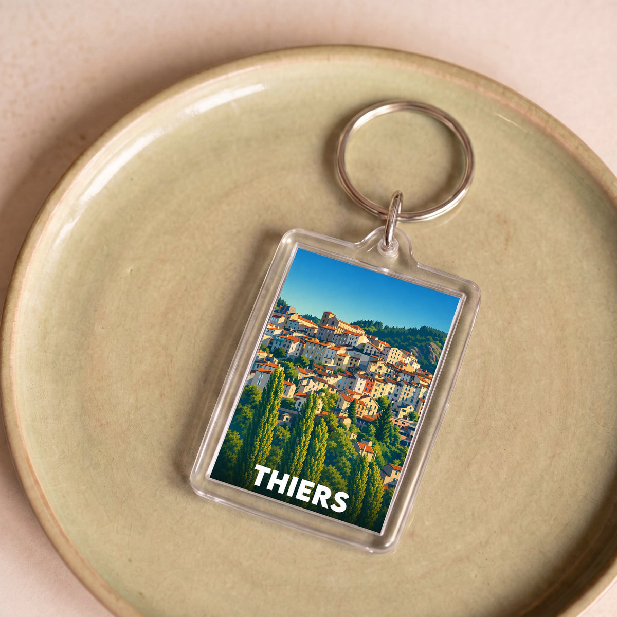 Porte-clés souvenir de la ville de Thiers avec une illustration stylisée de ses maisons à flanc de colline.