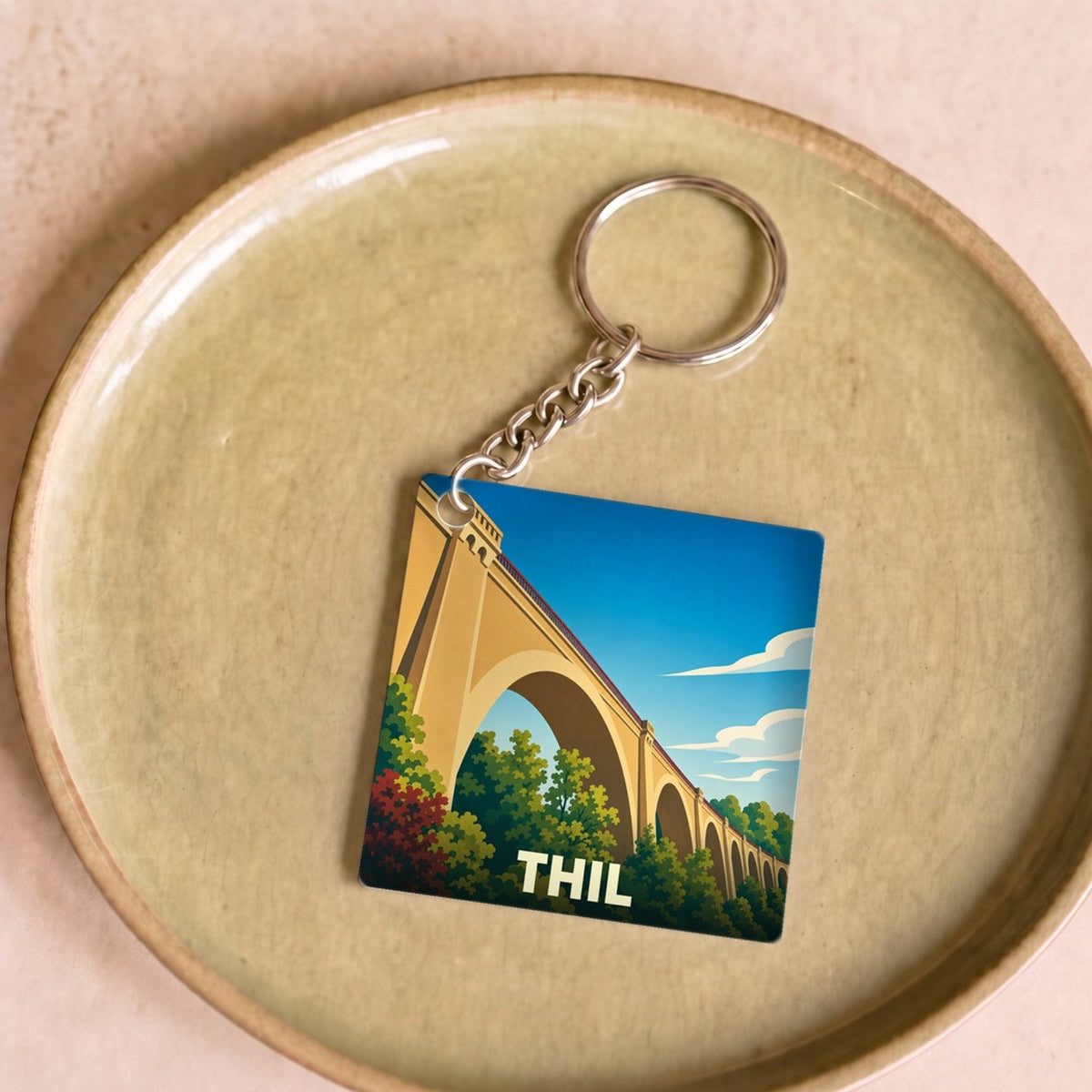 Porte-clés souvenir de la ville de Thil avec une illustration stylisée d'un viaduc.