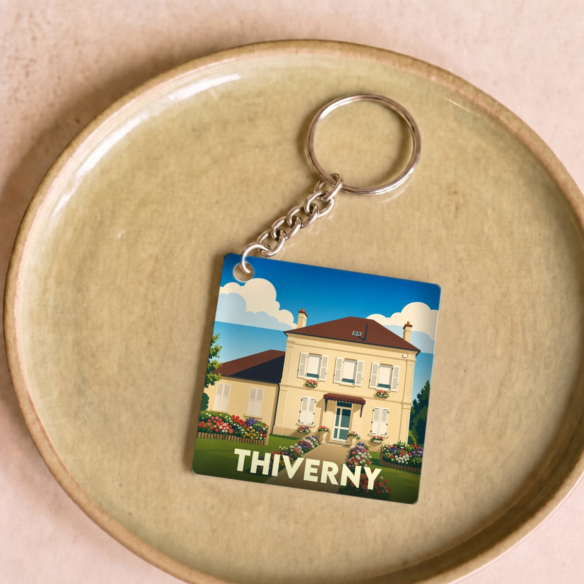 Porte-clés souvenir de la ville de Thiverny avec une illustration stylisée d'une maison fleurie.