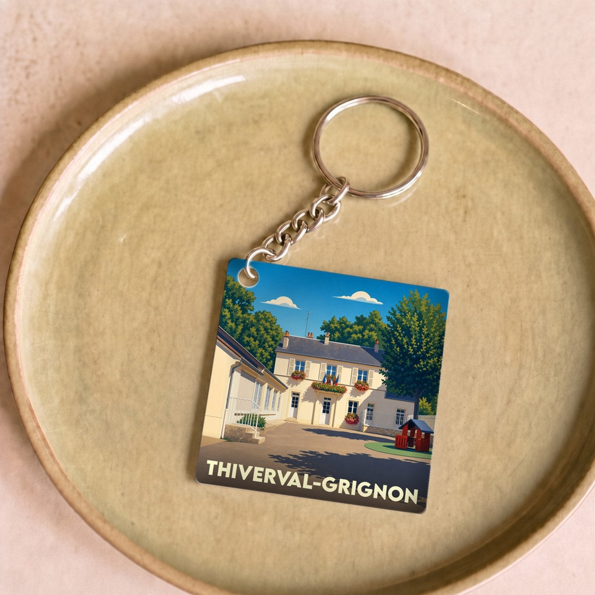 Porte-clés souvenir de la ville de Thiverval-Grignon avec une illustration stylisée d'une maison de ville.