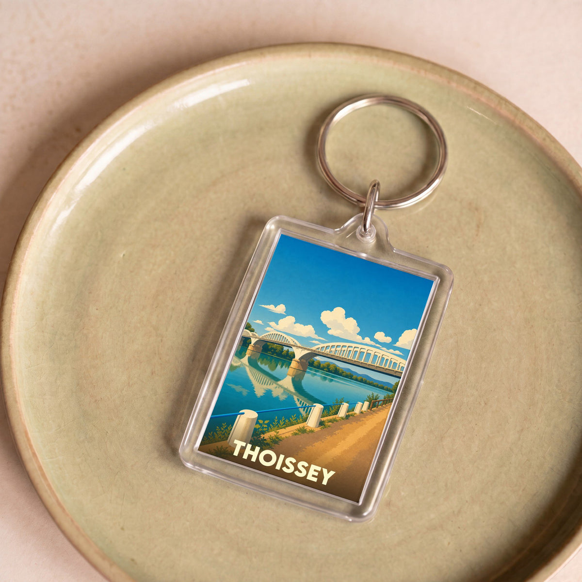 Porte-clés souvenir de la ville de Thoissey illustrant son pont sur la Saône dans un style graphique épuré.