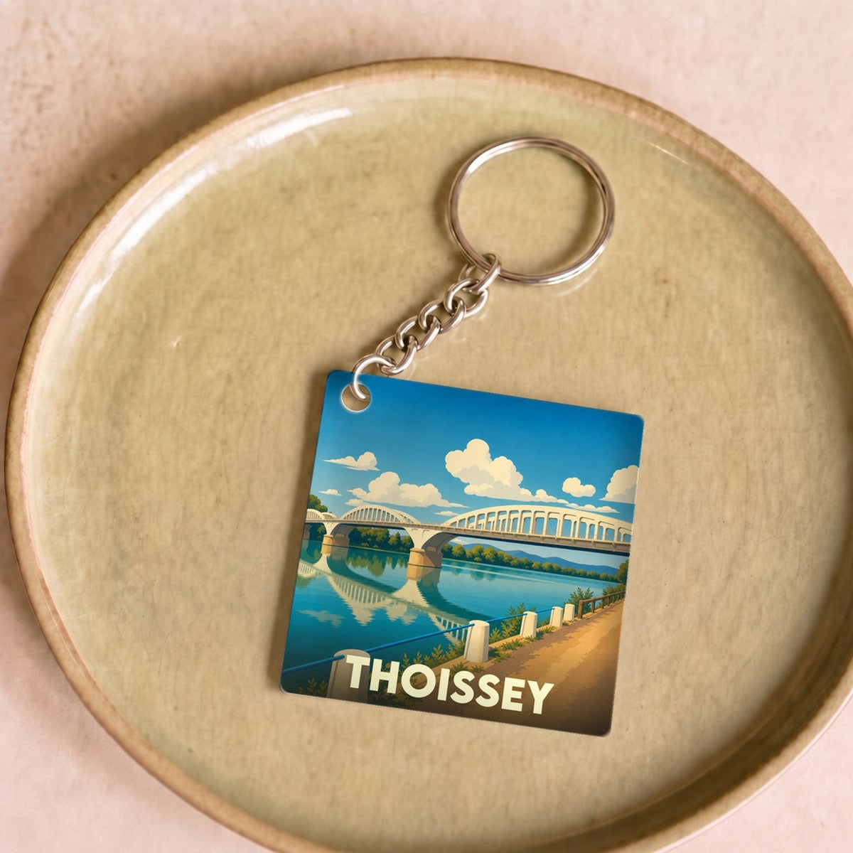 Porte-clés souvenir de la ville de Thoissey illustrant son pont sur la Saône dans un style graphique épuré.