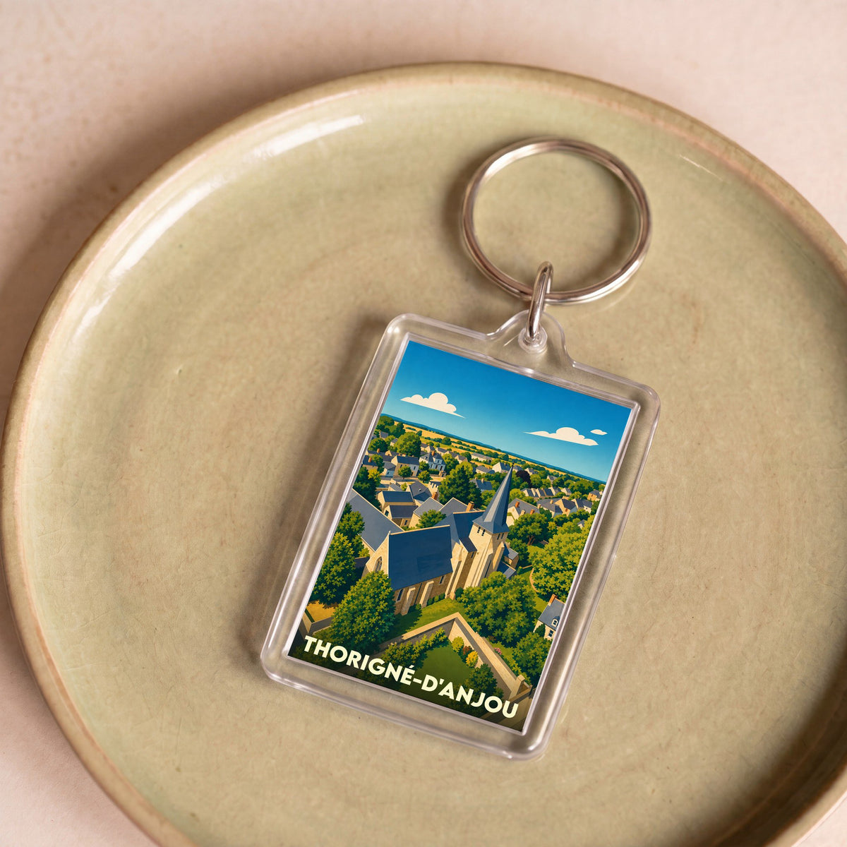 Porte-clés souvenir de la ville de Thorigné-d'Anjou avec une illustration stylisée.