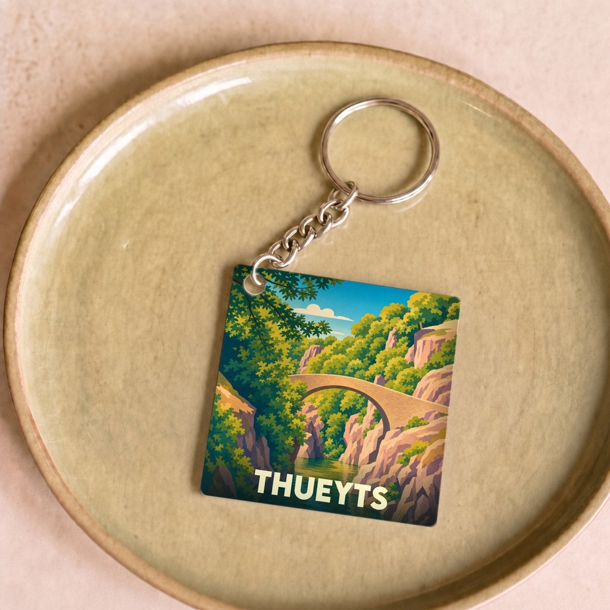 Porte-clés souvenir de la ville de Thueyts avec une illustration stylisée d'un pont en pierre surplombant des gorges.