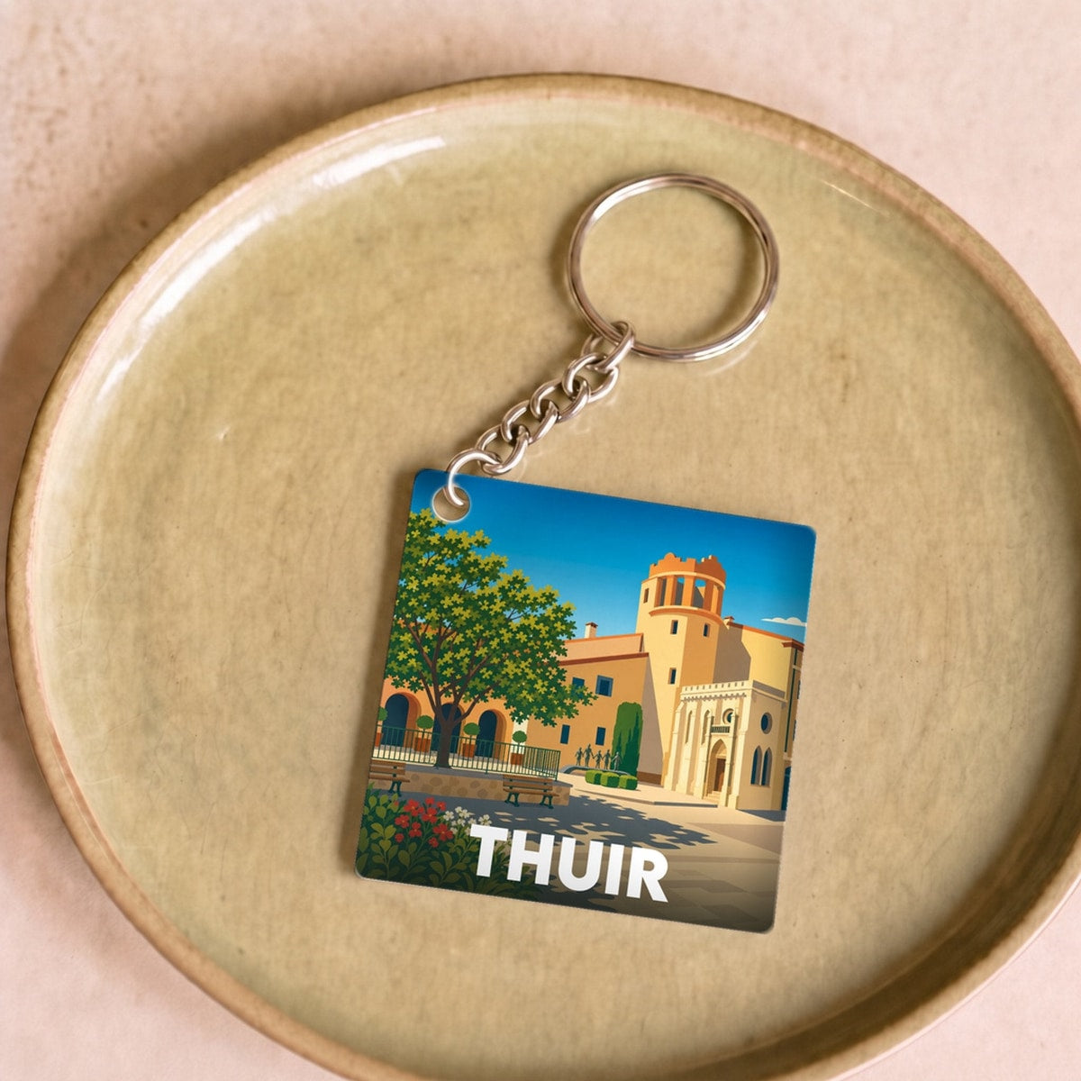 Porte-clés souvenir de la ville de Thuir avec une illustration stylisée.