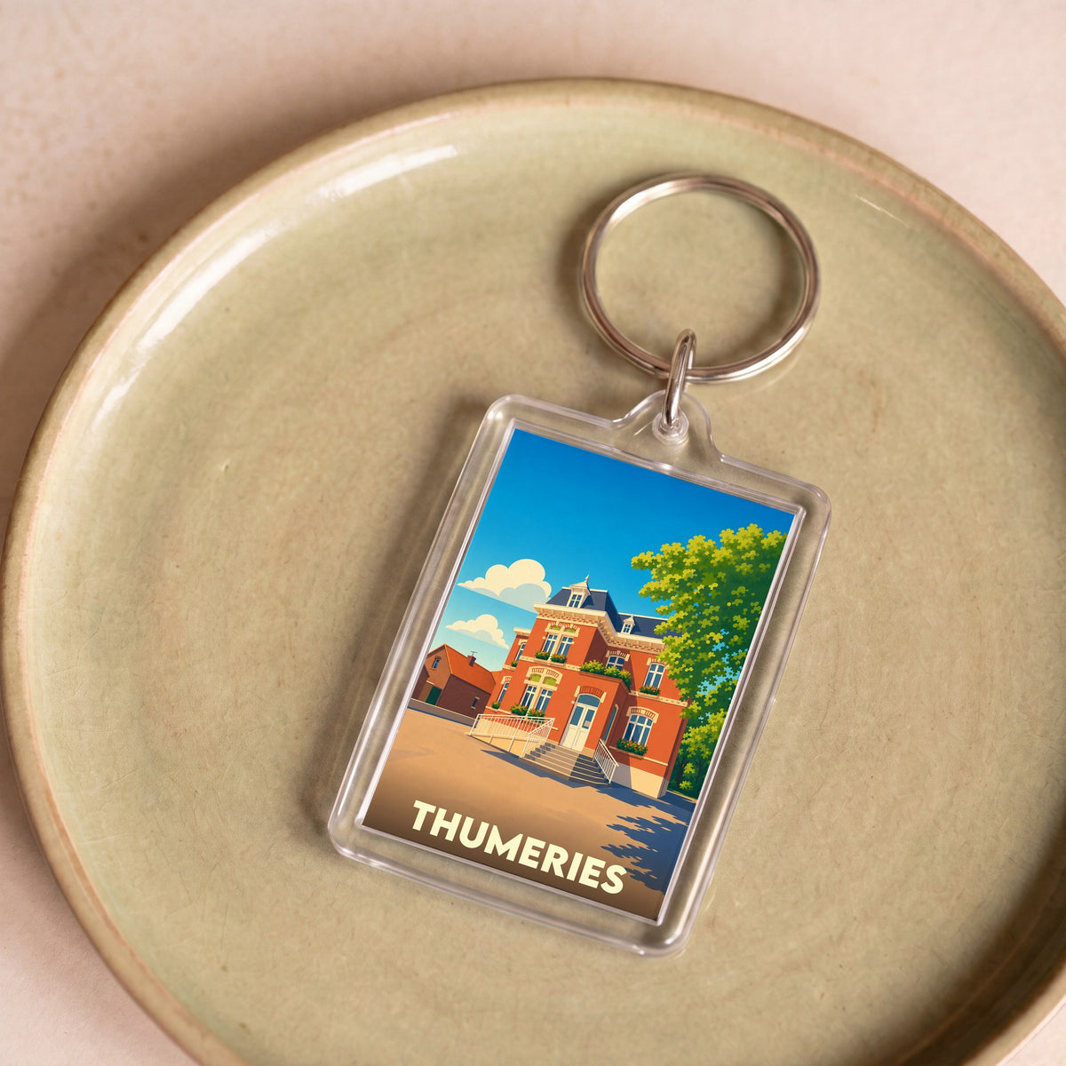 Porte-clés souvenir de la ville de Thumeries avec une illustration stylisée d'un bâtiment historique.