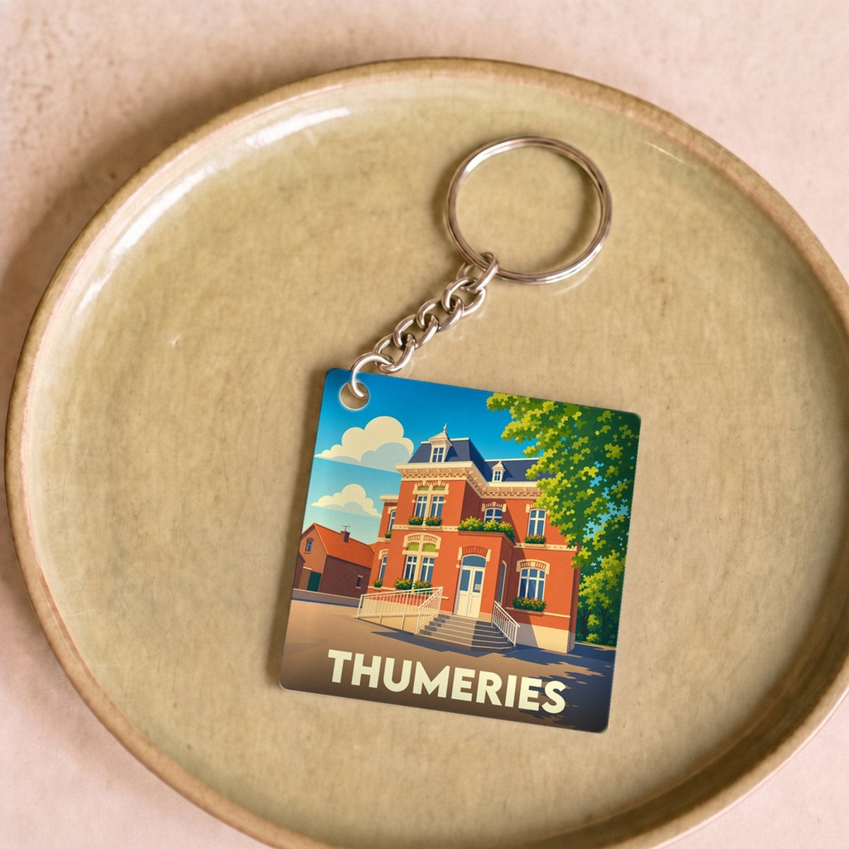 Porte-clés souvenir de la ville de Thumeries avec une illustration stylisée d'un bâtiment historique.