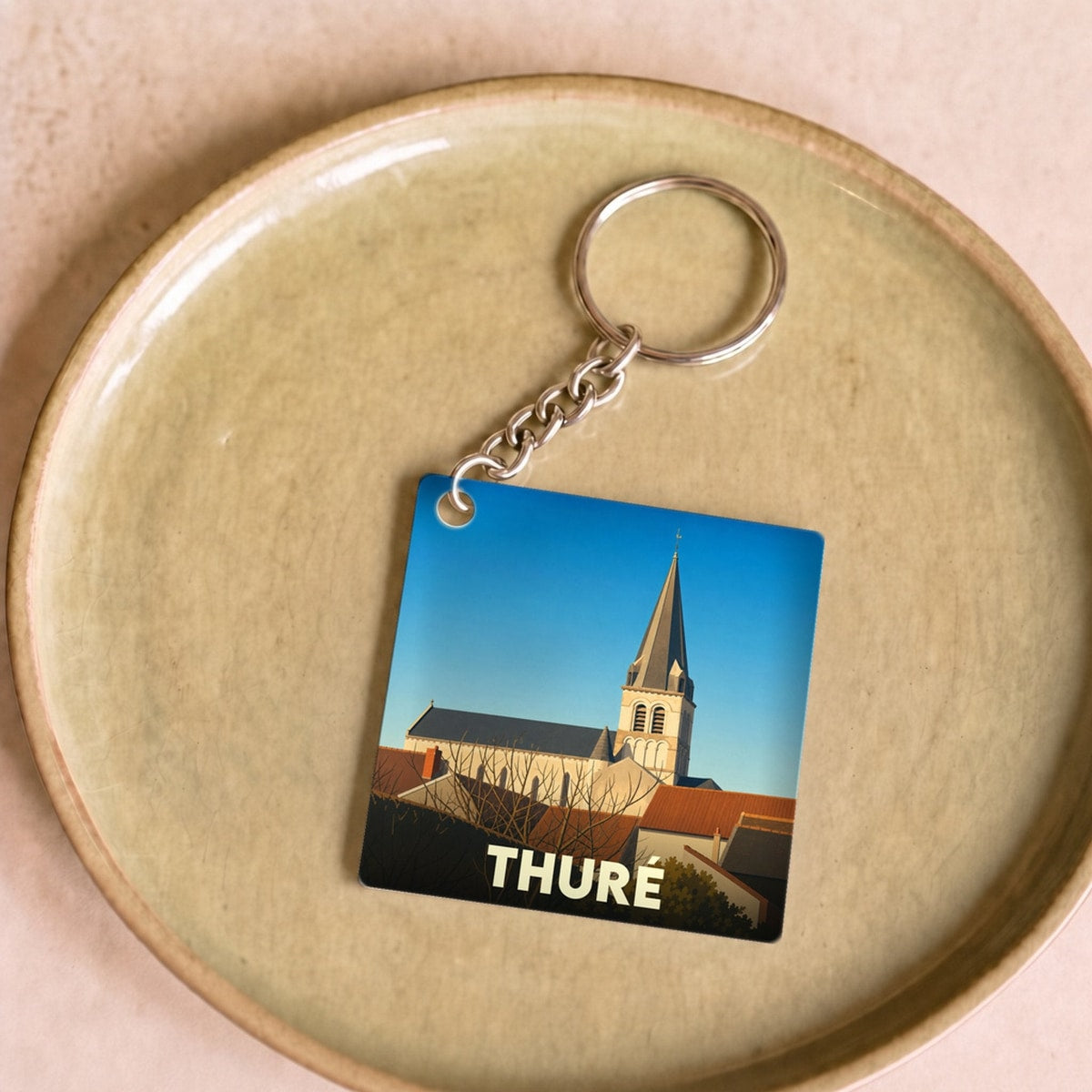 Porte-clés souvenir de la ville de Thuré avec une illustration stylisée de son église.
