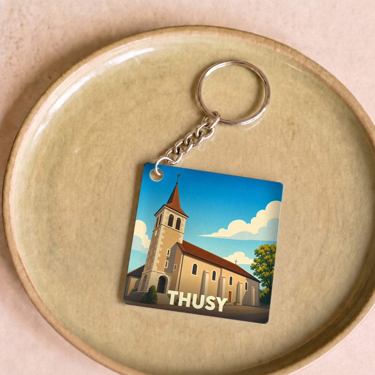 Porte-clés souvenir de la ville de Thusy avec une illustration stylisée de son église.