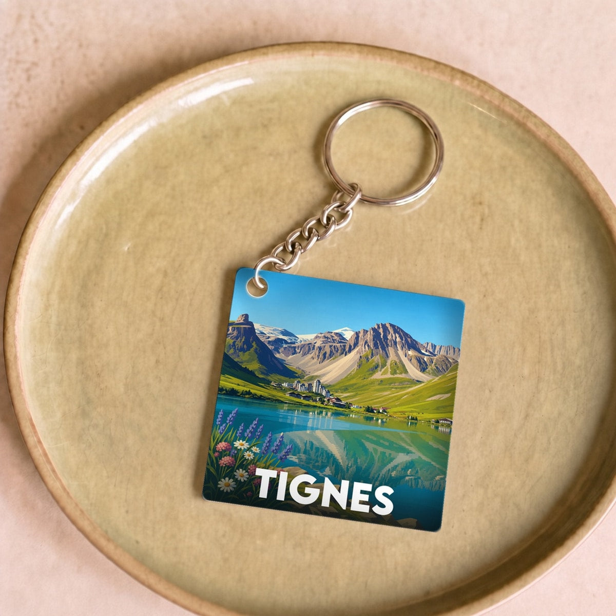 Porte-clés souvenir de la ville de Tignes avec une illustration stylisée de paysage de montagne.