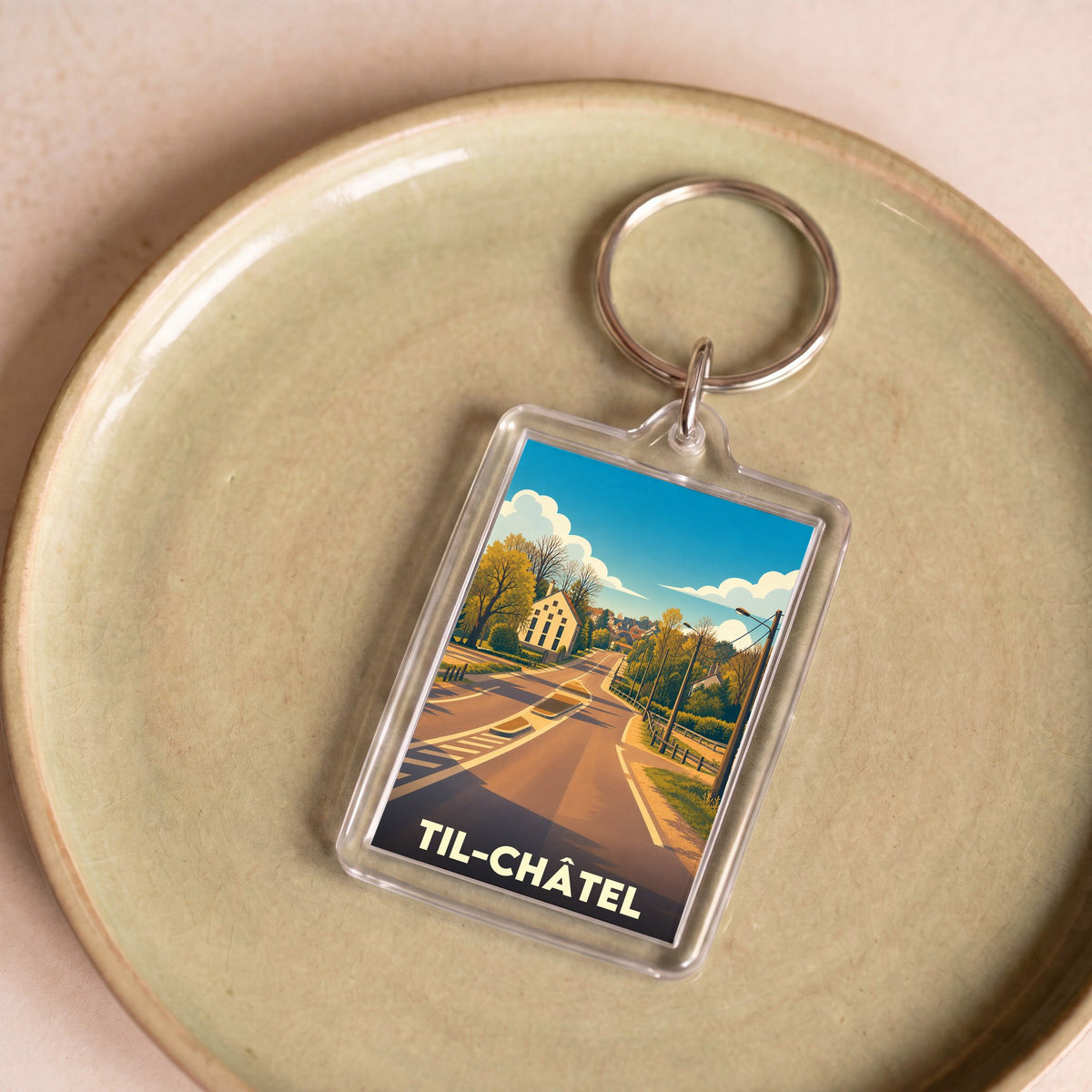 Porte-clés souvenir de la ville de Til-Châtel avec une illustration stylisée.