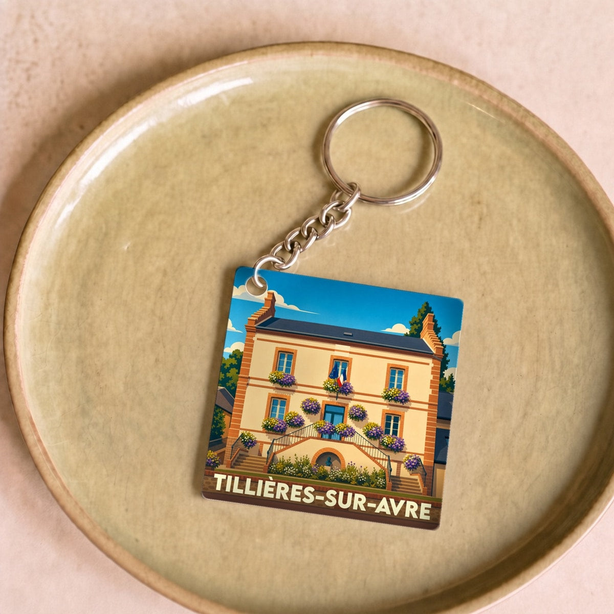 Porte-clés souvenir de la ville de Tillières-sur-Avre avec une illustration stylisée.