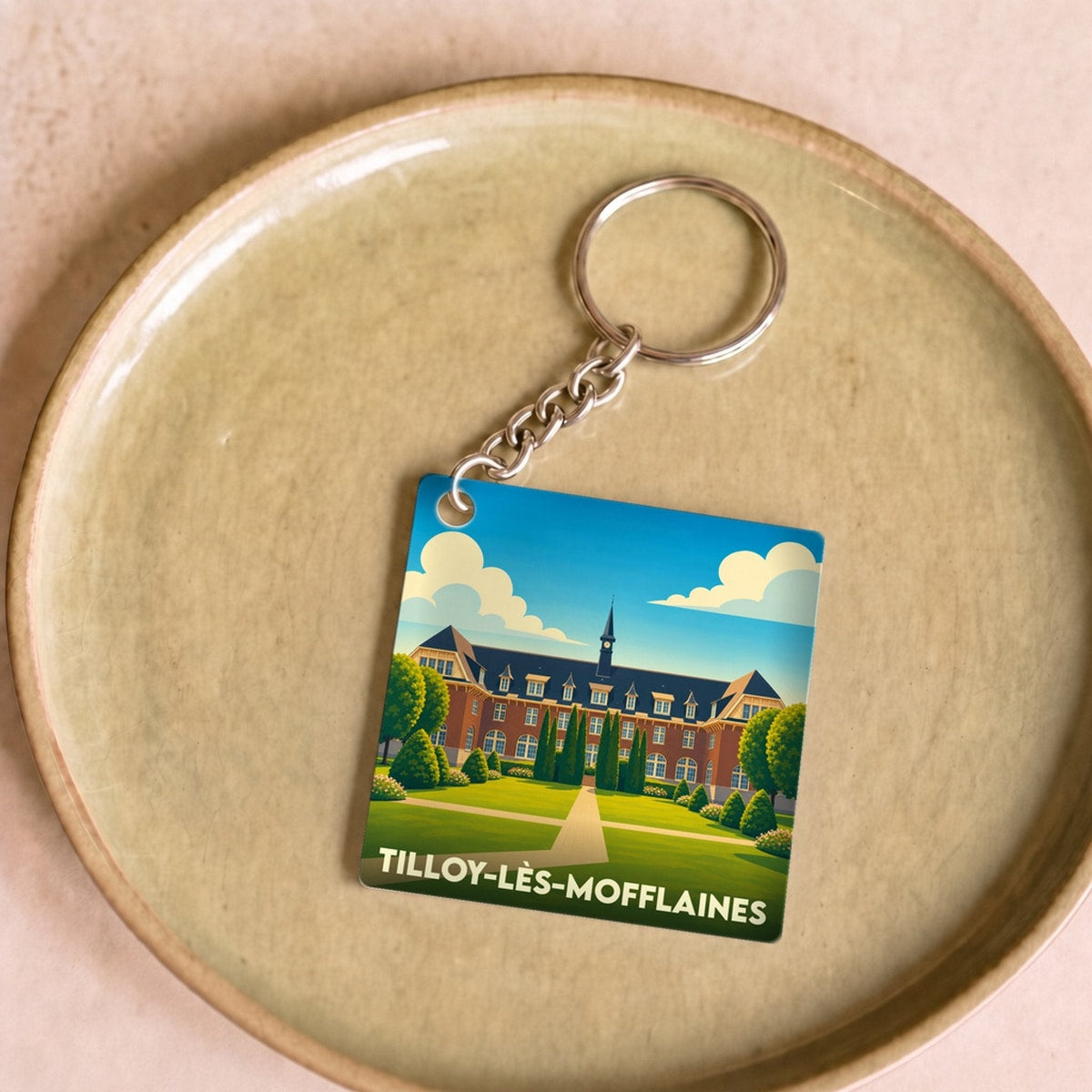 Porte-clés souvenir de la ville de Tilloy-lès-Mofflaines avec une illustration stylisée.