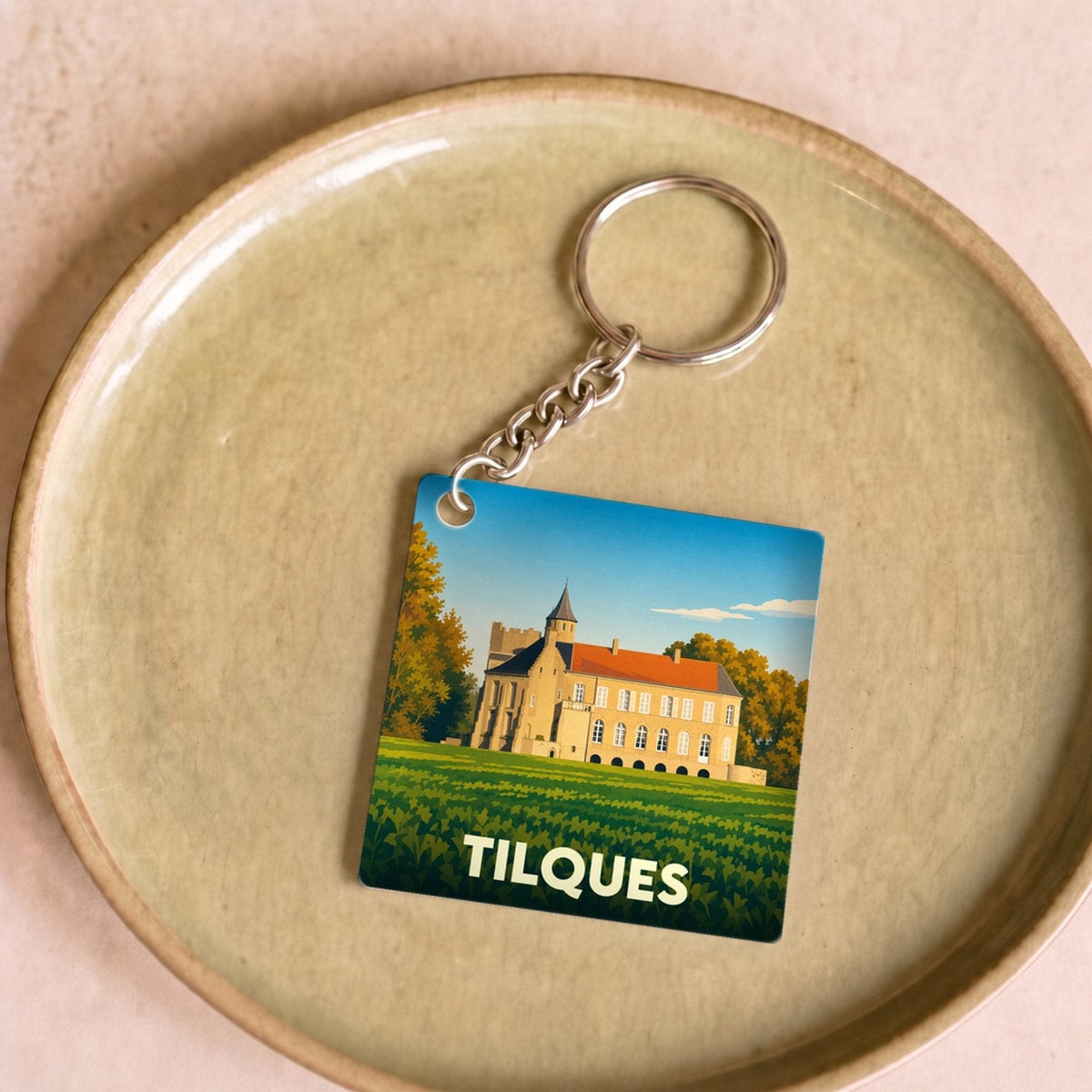 Porte-clés souvenir de la ville de Tilques avec une illustration stylisée de son château.