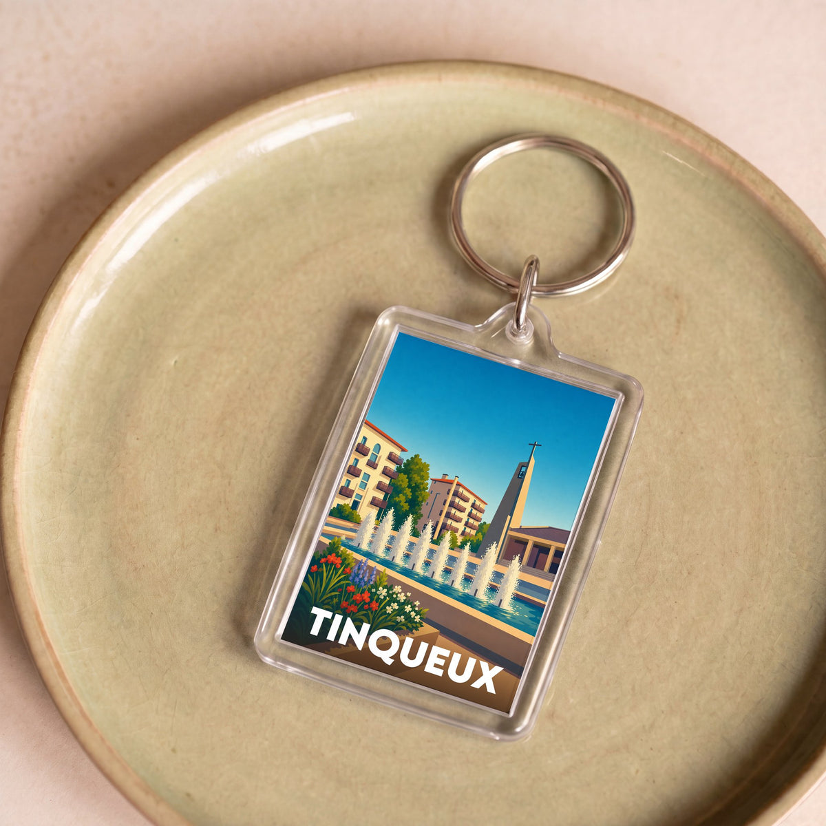 Porte-clés souvenir de la ville de Tinqueux avec une illustration stylisée.