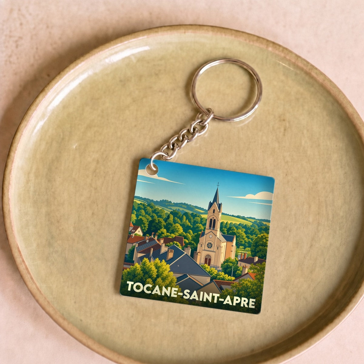 Porte-clés souvenir de la ville de Tocane-Saint-Apre avec une illustration stylisée de son église et de ses paysages.