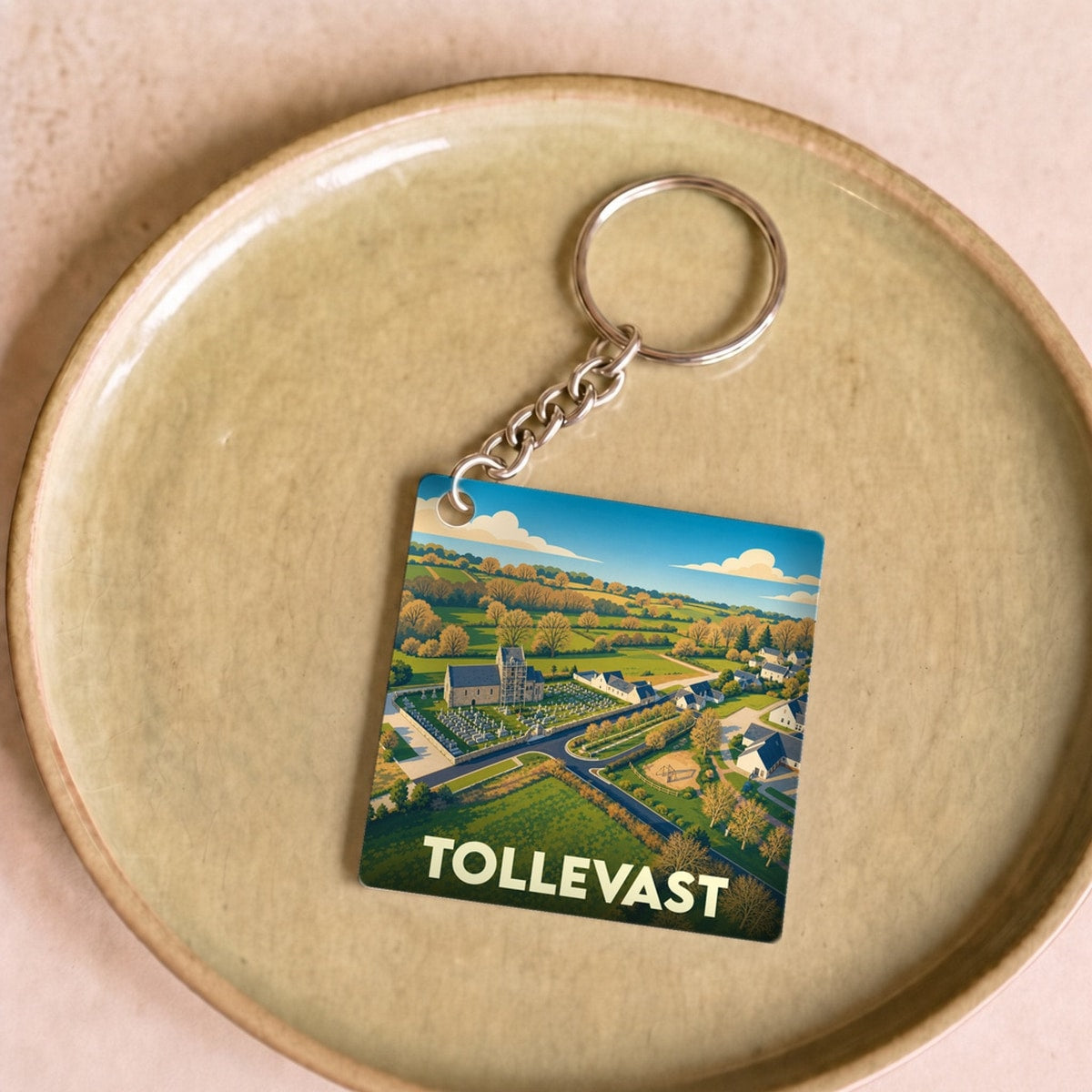 Porte-clés souvenir de la ville de Tollevast avec une illustration paysagère stylisée.