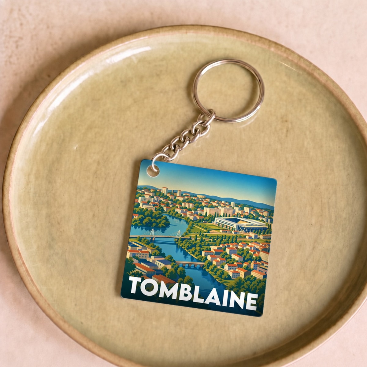 Porte-clés souvenir de la ville de Tomblaine avec une illustration panoramique colorée.