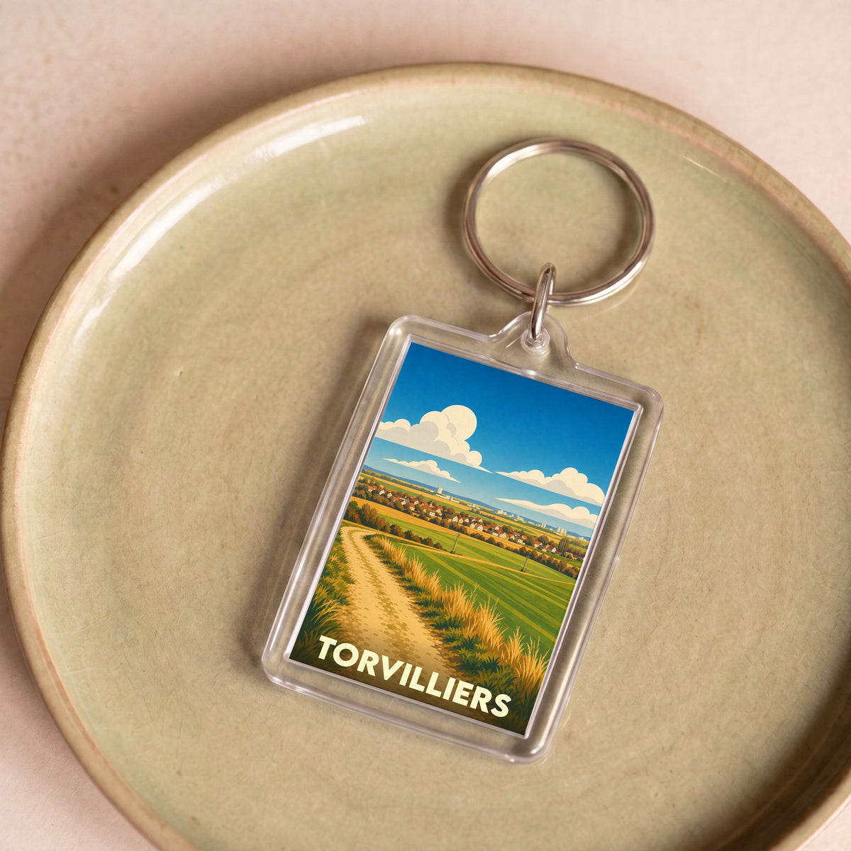 Porte-clés souvenir de la ville de Torvilliers avec une illustration stylisée de son paysage champêtre.