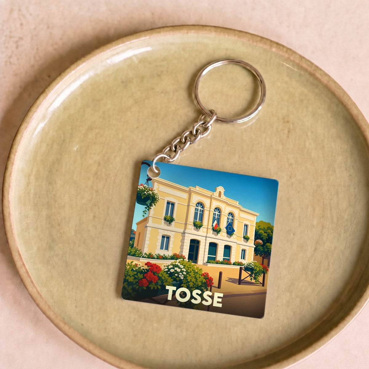 Porte-clés souvenir de la ville de Tosse avec une illustration stylisée de sa mairie.