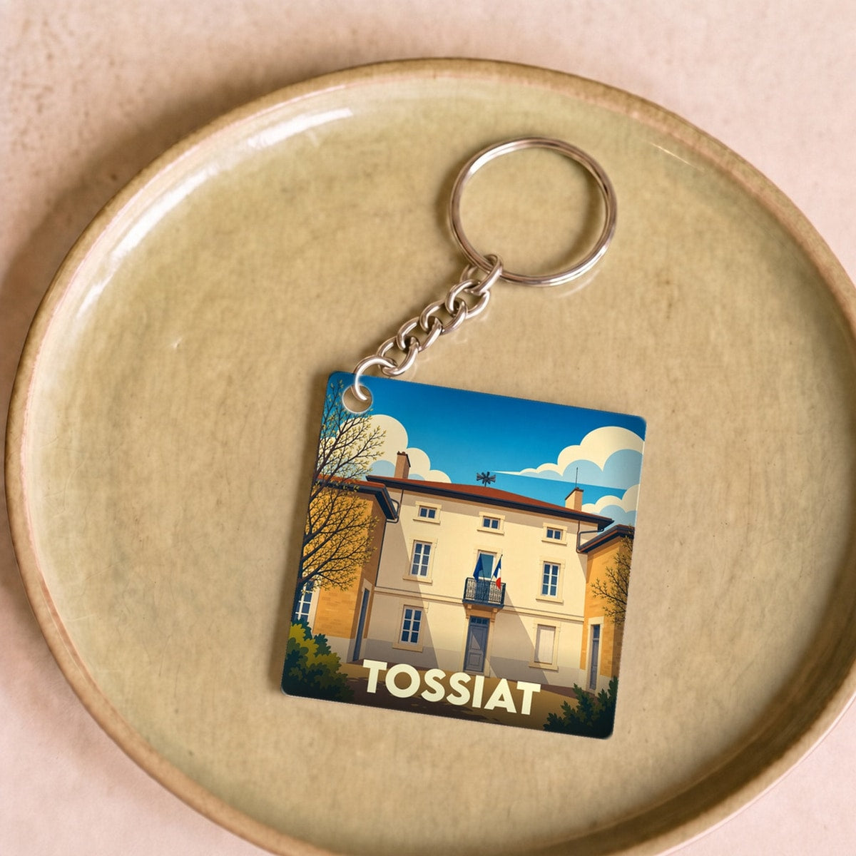 Porte-clés souvenir de la ville de Tossiat avec une illustration stylisée d'un bâtiment emblématique.