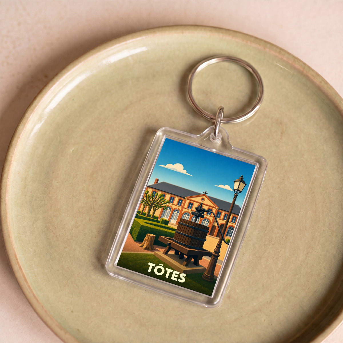 Porte-clés souvenir de la ville de Tôtes avec une illustration stylisée.