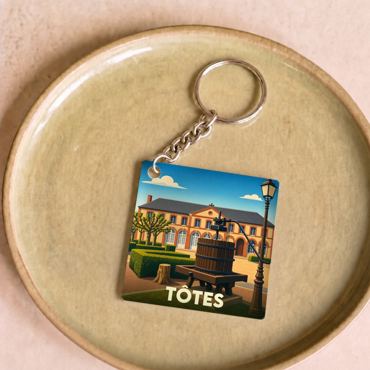 Porte-clés souvenir de la ville de Tôtes avec une illustration stylisée.