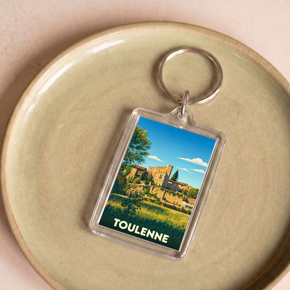 Porte-clés souvenir de la ville de Toulenne avec une illustration stylisée.
