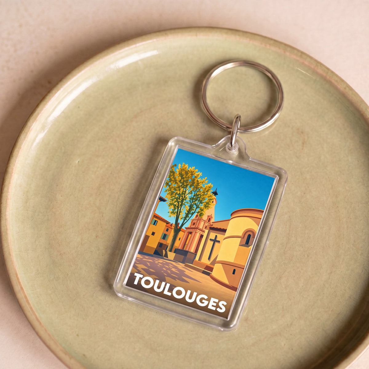 Porte-clés souvenir de la ville de Toulouges avec une illustration stylisée.