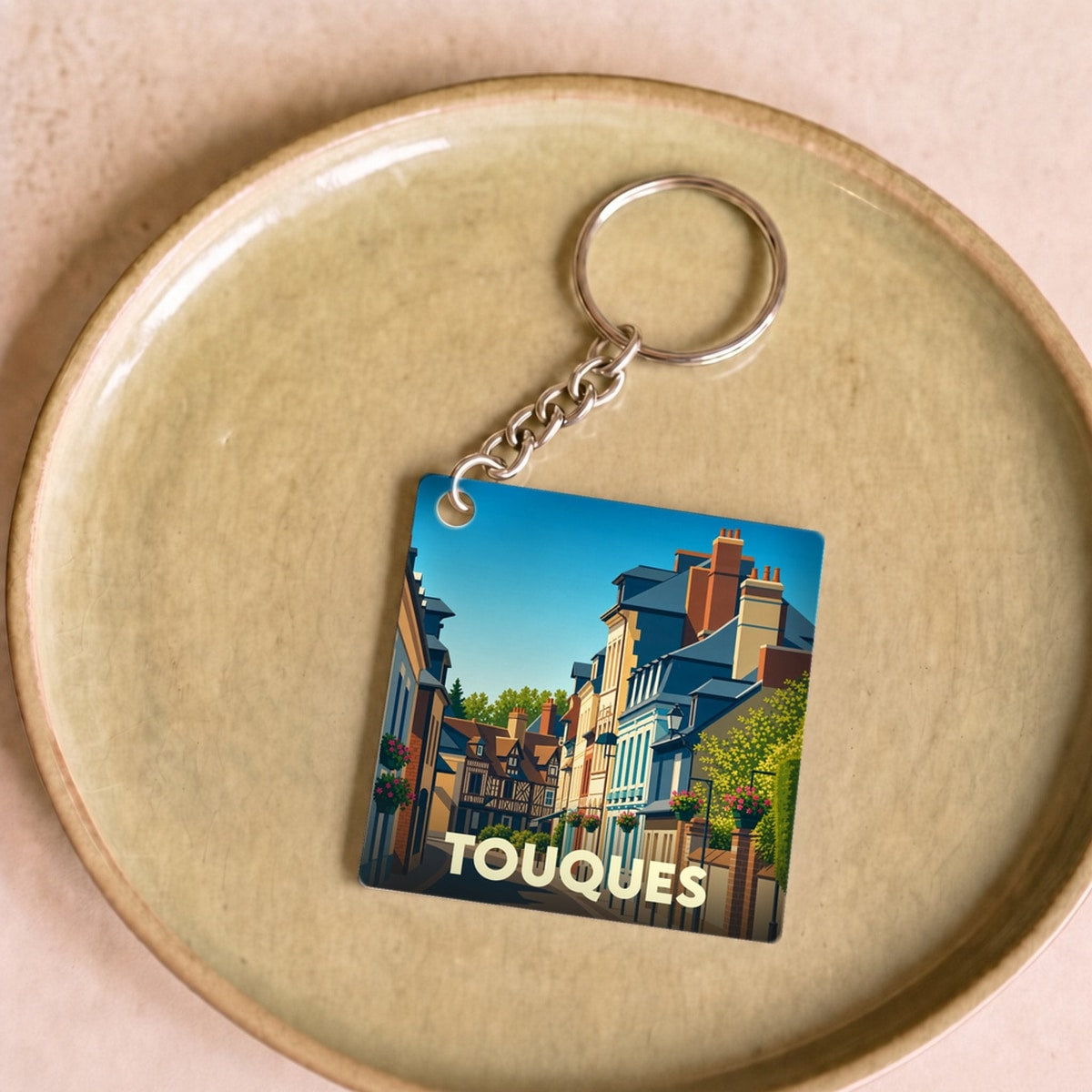 Porte-clés souvenir de la ville de Touques avec une illustration stylisée d'une rue typique.