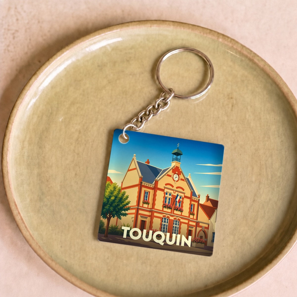 Porte-clés souvenir de la ville de Touquin avec une illustration stylisée de sa mairie.