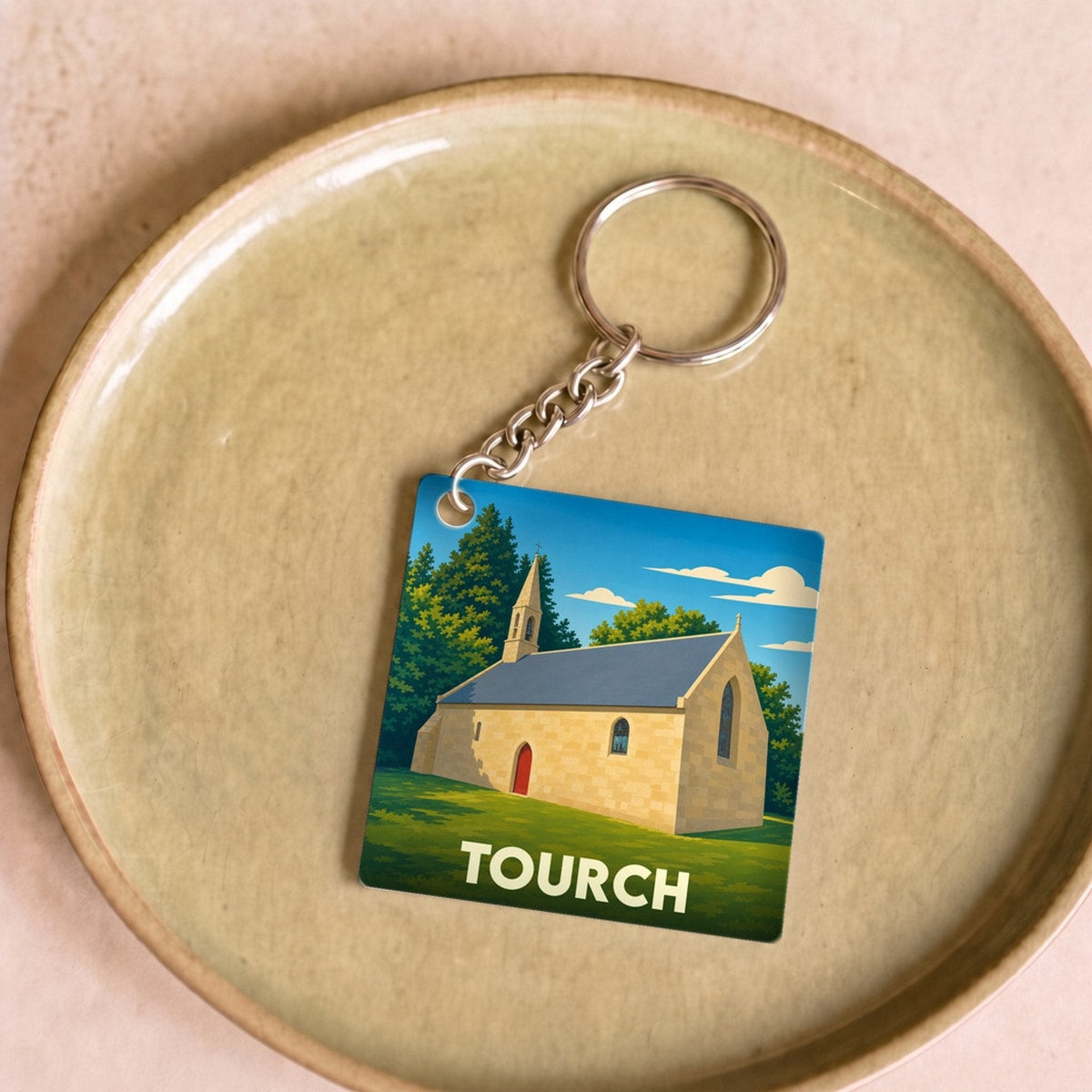 Porte-clés souvenir de la ville de Tourch avec une illustration stylisée d'une chapelle.