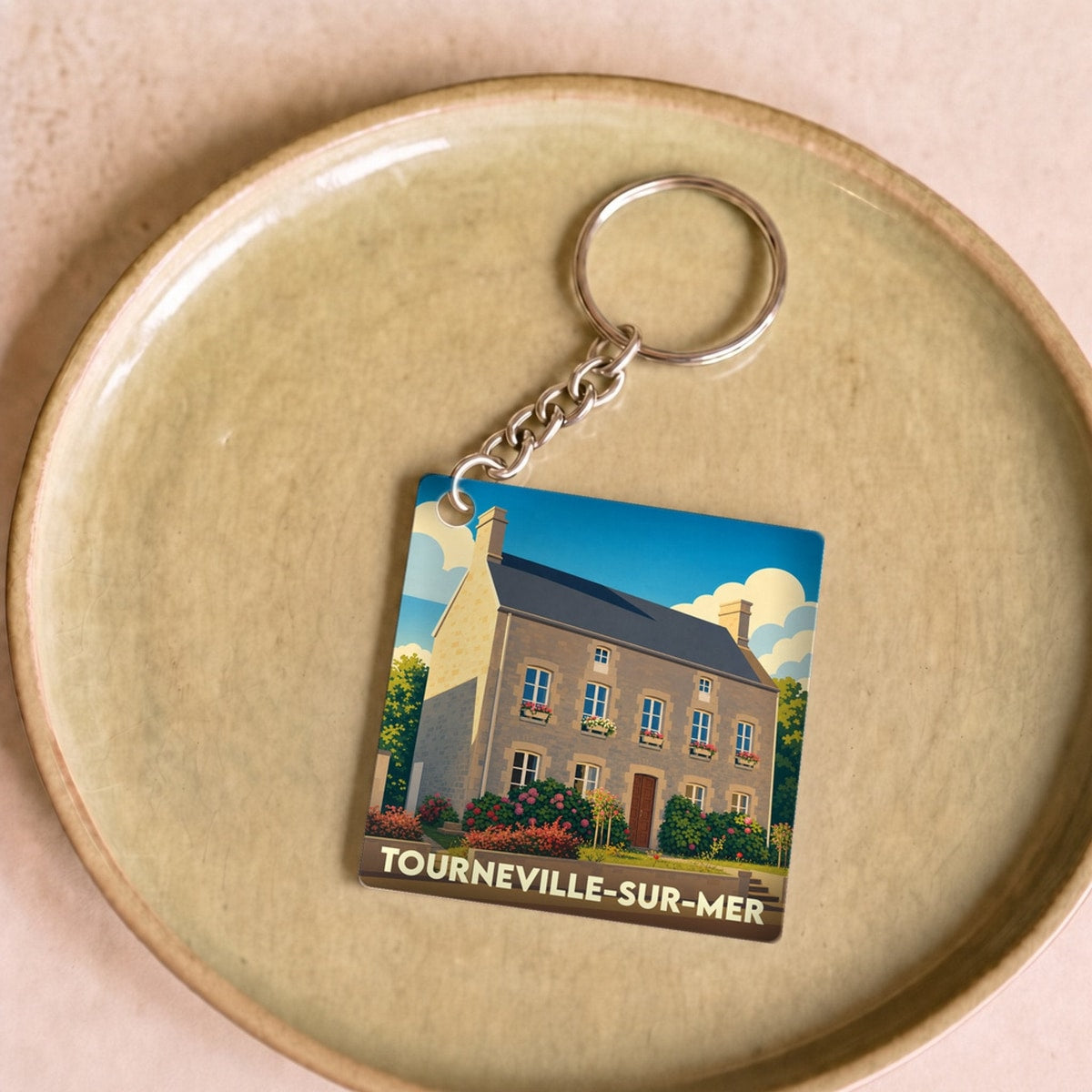 Porte-clés souvenir de la ville de Tourneville-sur-Mer avec une illustration stylisée d'une maison côtière.