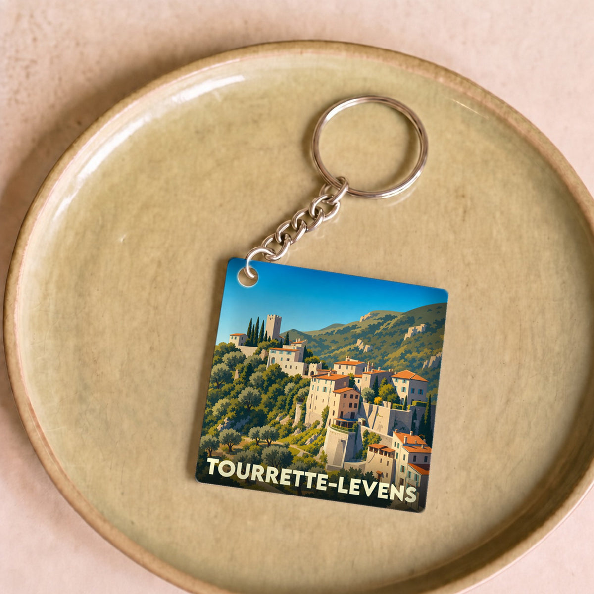 Porte-clés souvenir de la ville de Tourrette-Levens avec une illustration stylisée.