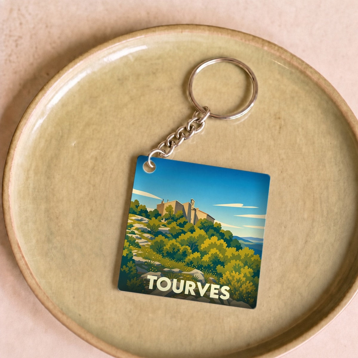 Porte-clés souvenir de la ville de Tourves avec une illustration stylisée de son paysage et de ses collines.