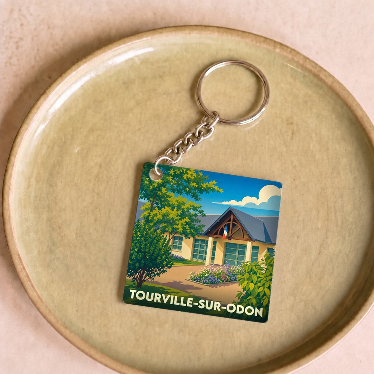 Porte-clés souvenir de la ville de Tourville-sur-Odon avec une illustration stylisée.