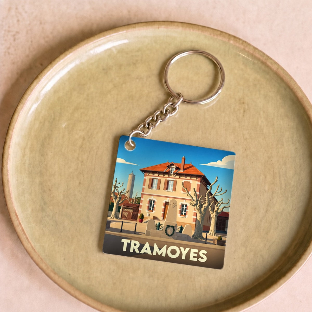 Porte-clés souvenir de la ville de Tramoyes avec une illustration stylisée.