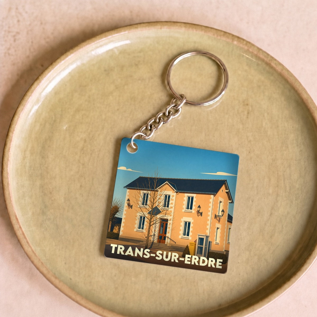 Porte-clés souvenir de la ville de Trans-sur-Erdre avec une illustration stylisée d'un bâtiment local.