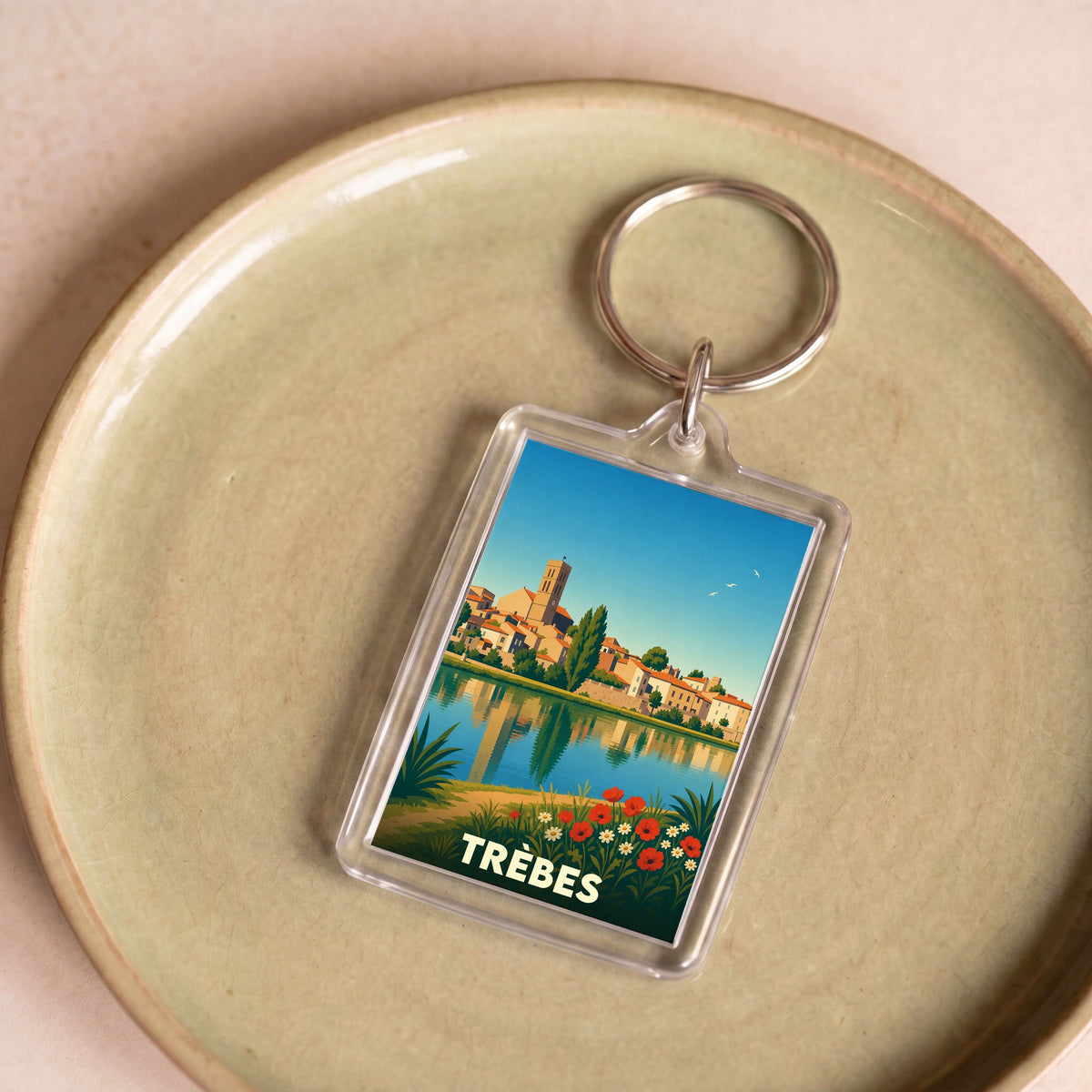 Porte-clés souvenir de la ville de Trèbes avec une illustration stylisée.
