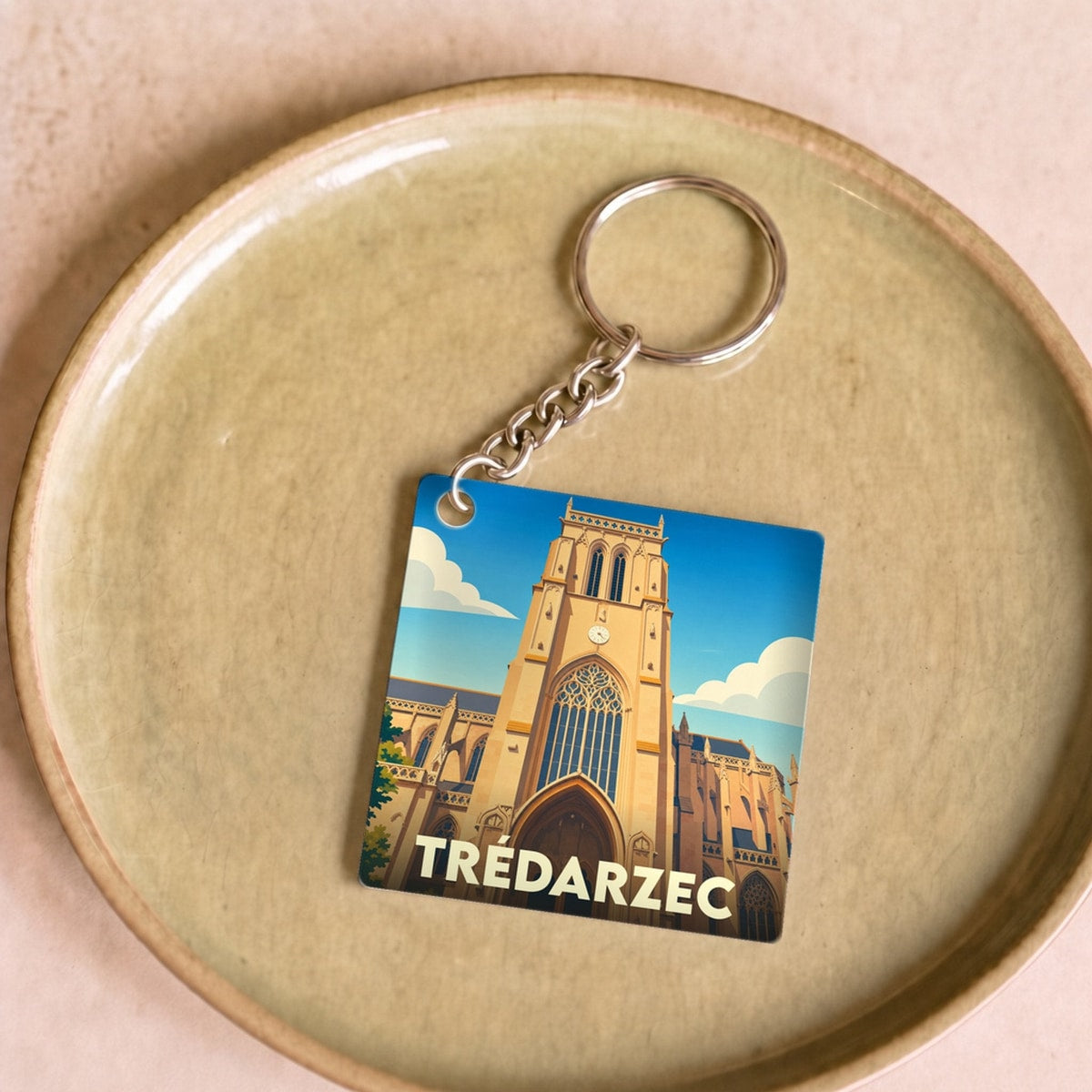 Porte-clés souvenir de la ville de Trédarzec avec une illustration stylisée de son église.
