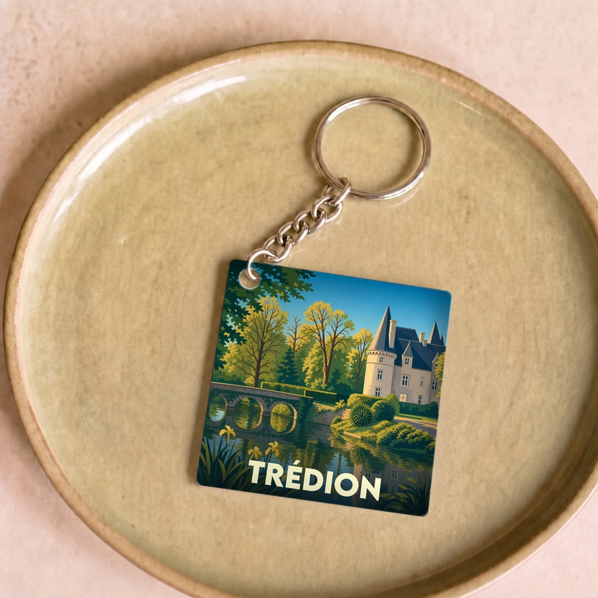Porte-clés souvenir de la ville de Trédion avec une illustration stylisée de son château et de son étang.