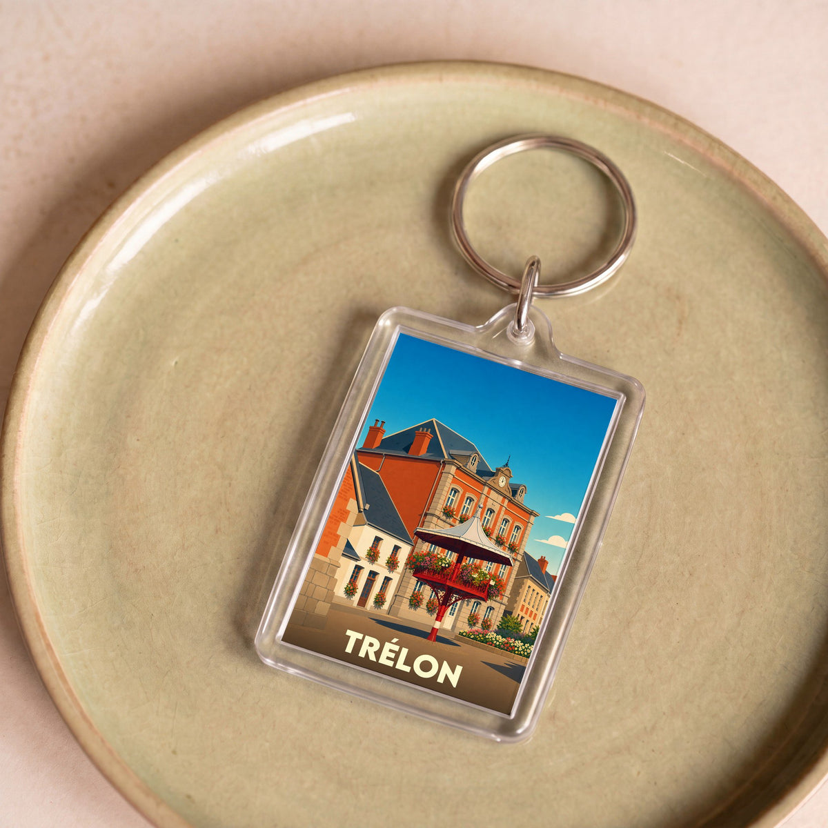 Porte-clés souvenir de la ville de Trélon avec une illustration stylisée de son architecture.