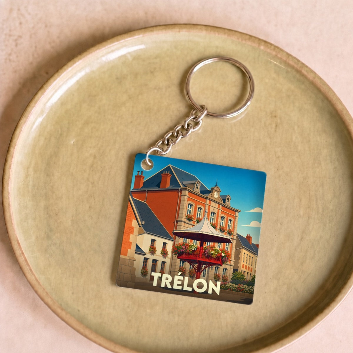 Porte-clés souvenir de la ville de Trélon avec une illustration stylisée de son architecture.