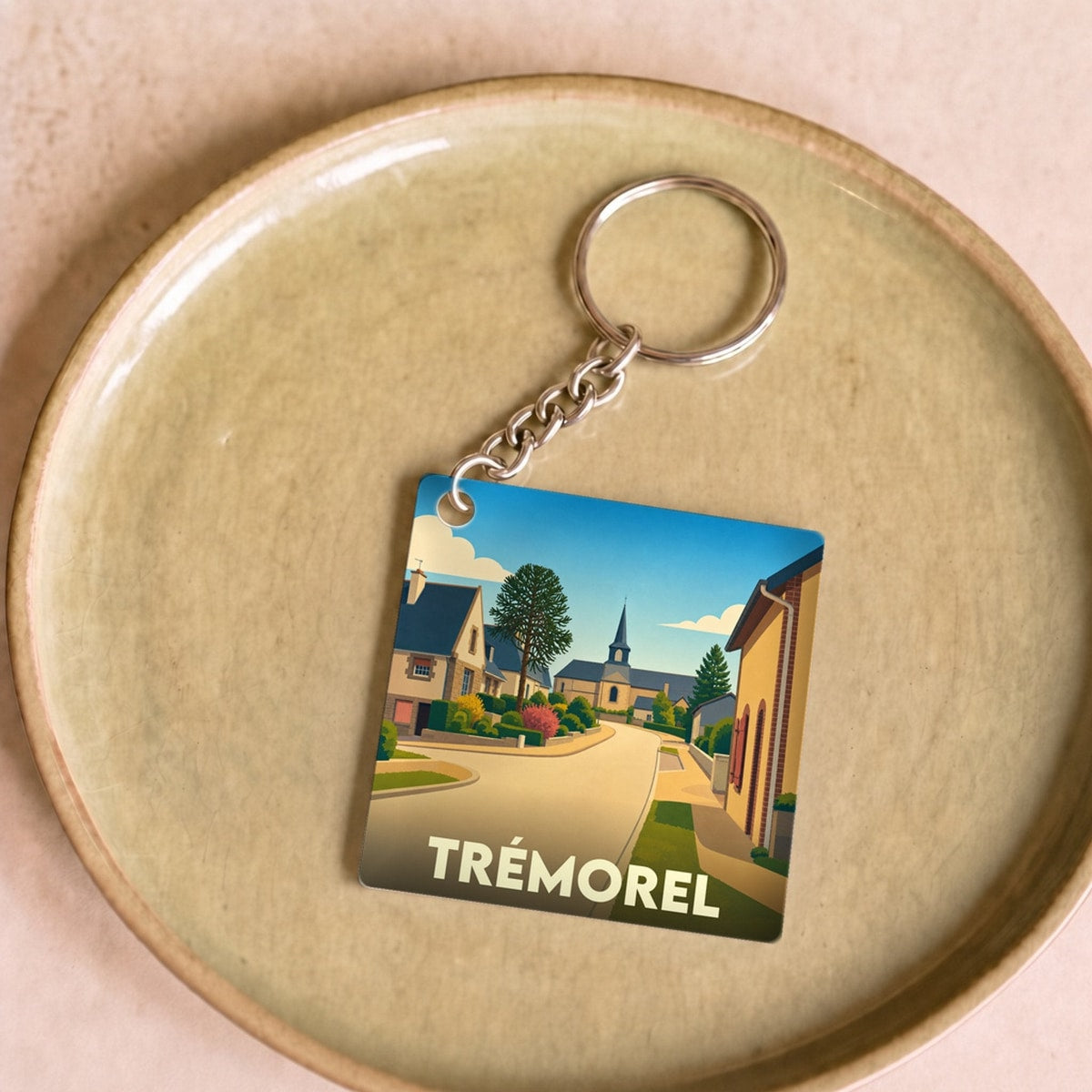 Porte-clés souvenir de la ville de Trémorel avec une illustration stylisée.