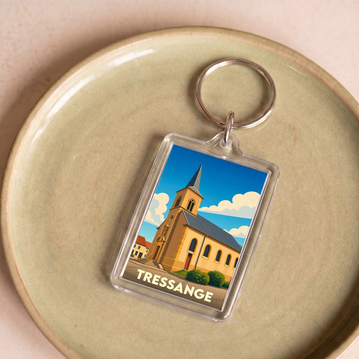 Porte-clés souvenir de la ville de Tressange avec une illustration stylisée de son église.